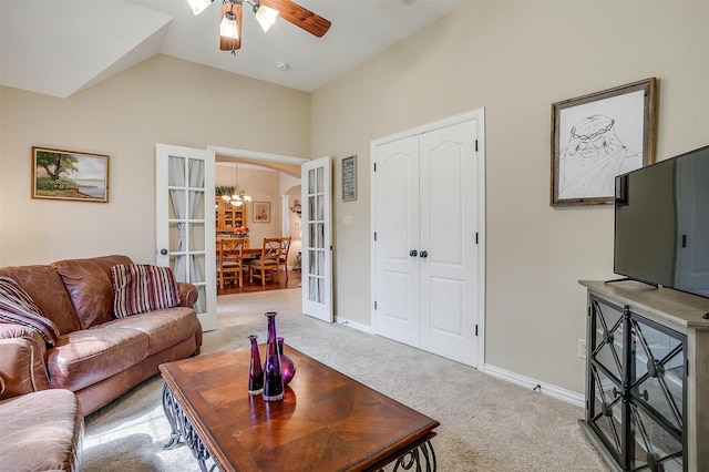 living area featuring lofted ceiling, arched walkways, light colored carpet, baseboards, and french doors