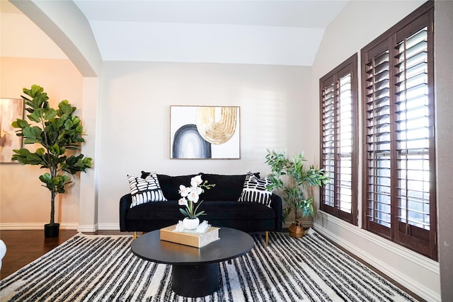 living room featuring lofted ceiling, wood finished floors, and baseboards