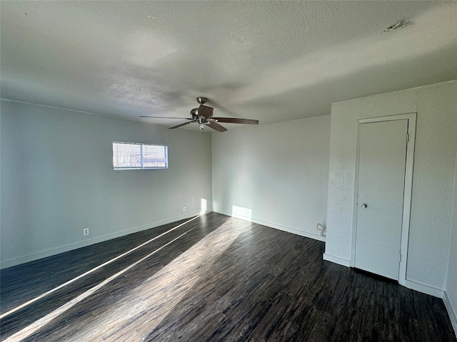 spare room with dark wood-style floors, a textured ceiling, and baseboards