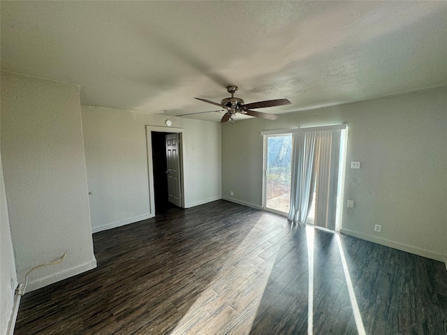 spare room with a textured ceiling, dark wood-type flooring, a ceiling fan, and baseboards