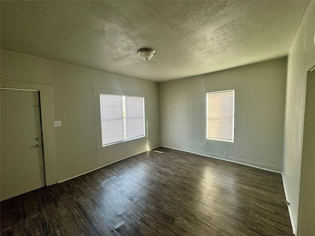 unfurnished room featuring a textured ceiling, dark wood finished floors, and baseboards