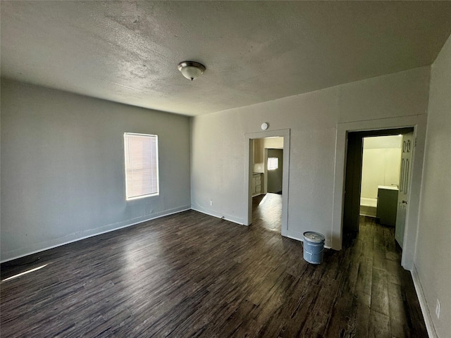 unfurnished bedroom featuring dark wood-style floors, a textured ceiling, and baseboards