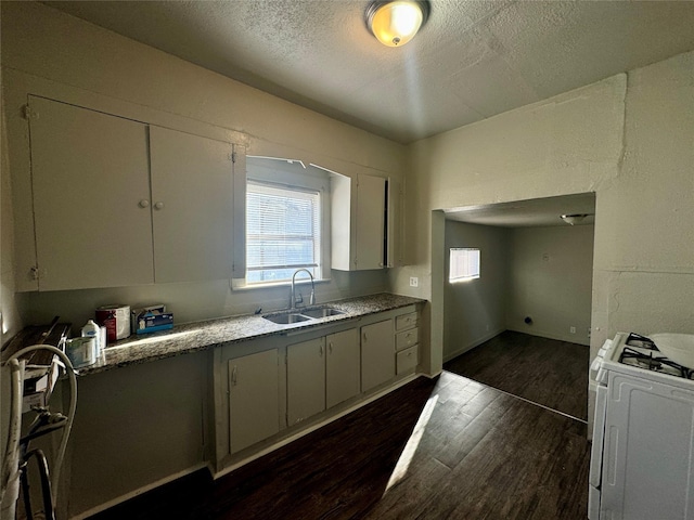 kitchen featuring white cabinets, dark wood-type flooring, white gas range, a textured ceiling, and a sink