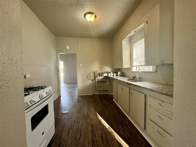 kitchen with a textured ceiling, a sink, light countertops, dark wood-style floors, and gas range gas stove