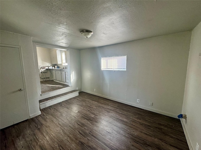 unfurnished bedroom with a textured ceiling, baseboards, and wood finished floors