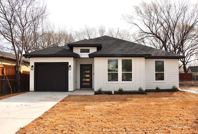 view of front facade featuring a garage, driveway, board and batten siding, and fence