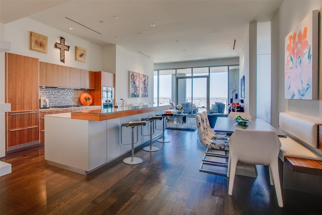 kitchen featuring a wall of windows, dark wood-style flooring, modern cabinets, and backsplash