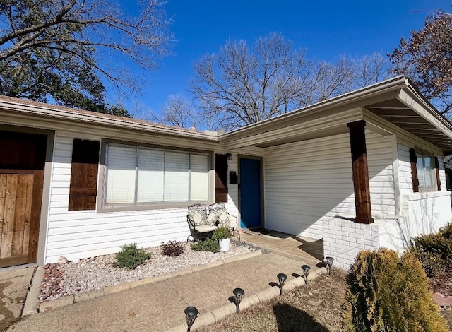 view of exterior entry featuring a garage and brick siding