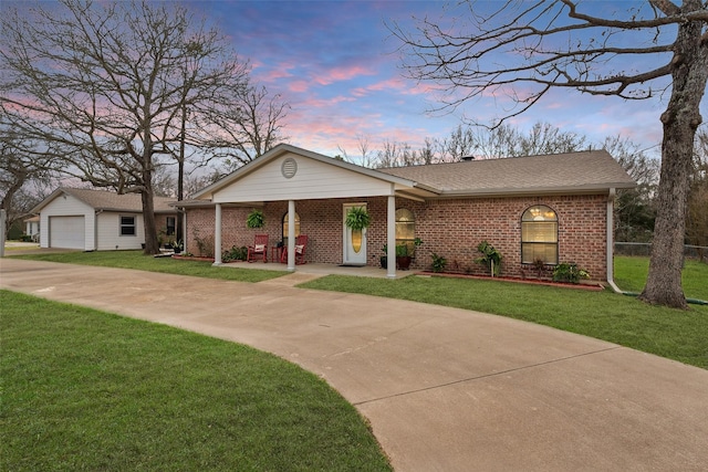 view of front facade with a porch, brick siding, concrete driveway, roof with shingles, and a front lawn