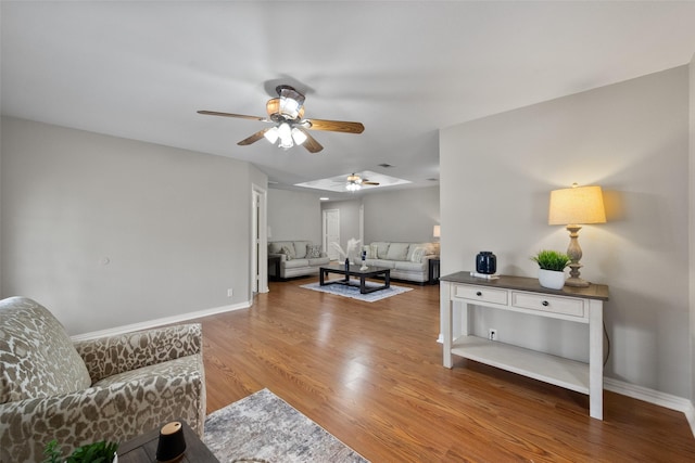 living area with ceiling fan, baseboards, and wood finished floors