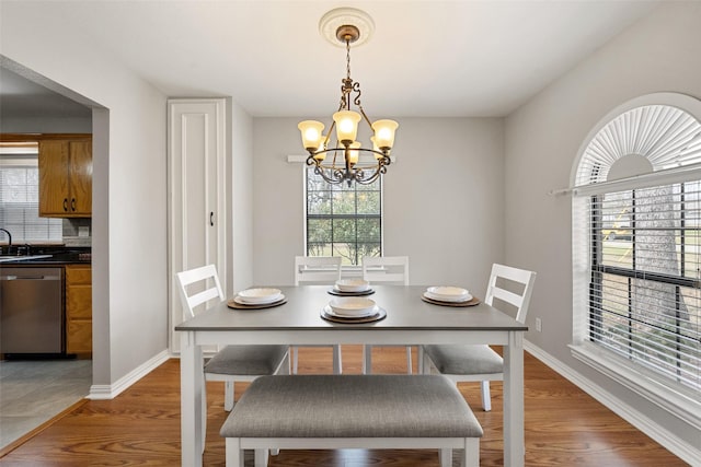 dining room with light wood-type flooring, baseboards, and a chandelier