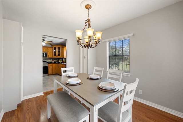 dining area featuring light wood-style flooring, baseboards, and a notable chandelier