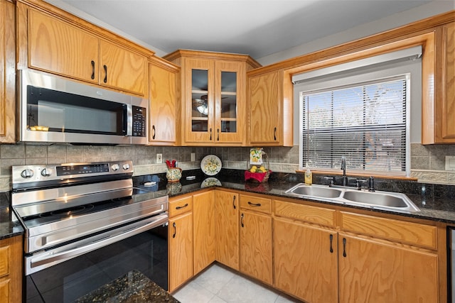 kitchen with light tile patterned floors, tasteful backsplash, glass insert cabinets, stainless steel appliances, and a sink