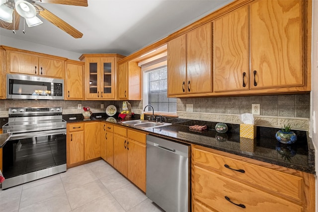 kitchen featuring light tile patterned floors, decorative backsplash, appliances with stainless steel finishes, glass insert cabinets, and a sink