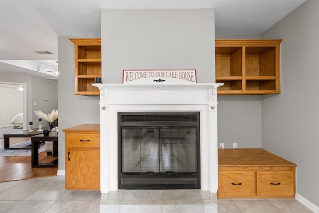 room details with ceiling fan, visible vents, baseboards, and a glass covered fireplace