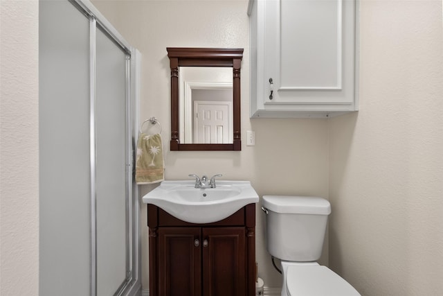 bathroom featuring vanity, a shower stall, and toilet