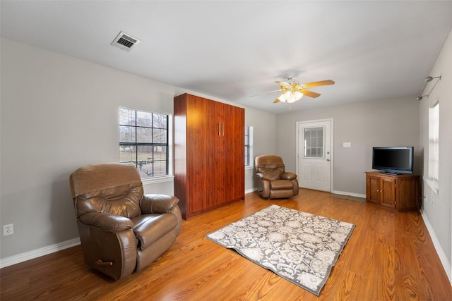 sitting room with light wood-style flooring, visible vents, ceiling fan, and baseboards