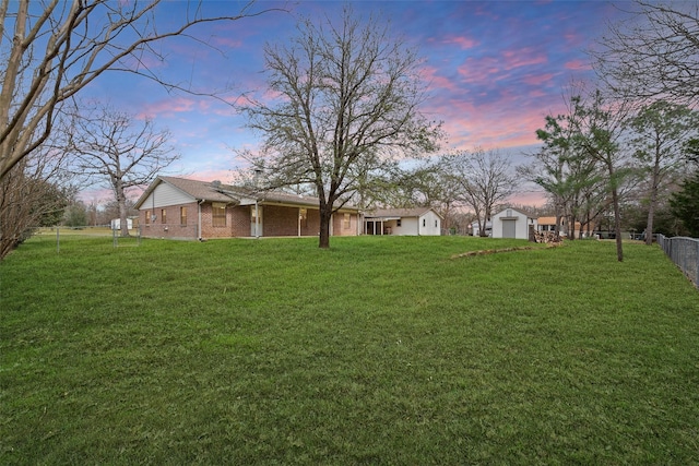 yard at dusk with a garage and fence