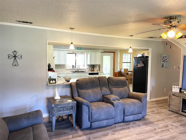 living room featuring a healthy amount of sunlight, light wood-type flooring, and crown molding