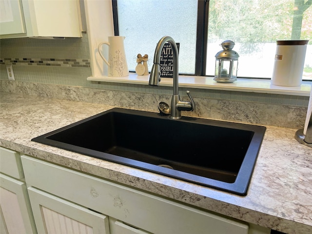 interior details featuring light countertops, a sink, and backsplash