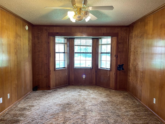 806 Robindale Ln, Fairfield, TX 75840 - carpeted empty room with crown molding, plenty of natural light, a textured ceiling, wooden walls, and ceiling fan