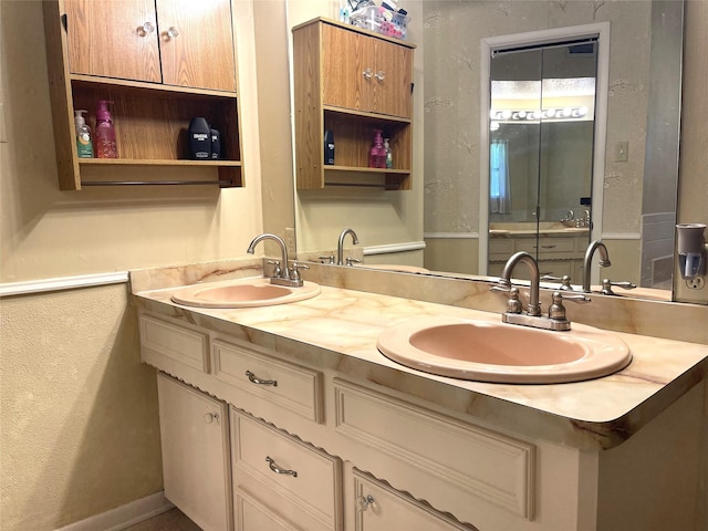 bathroom featuring a textured wall, double vanity, a sink, and baseboards