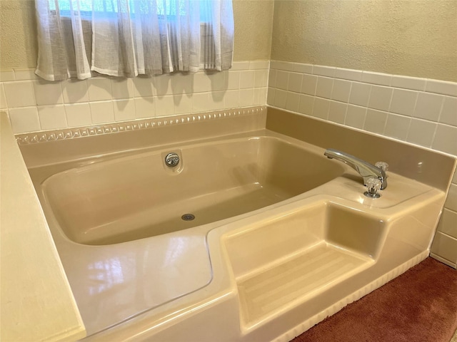 bathroom with a bath and a textured wall