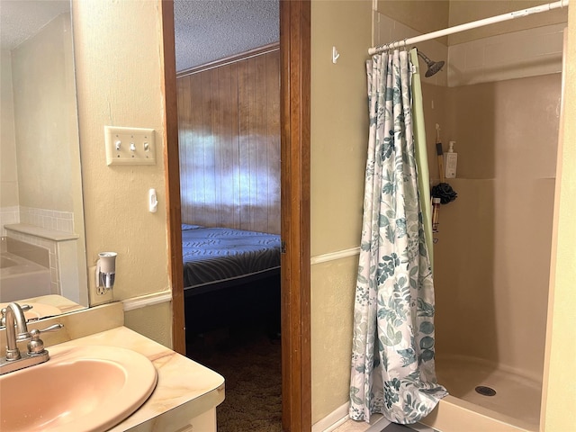 full bath with a textured wall, a shower stall, vanity, and a textured ceiling