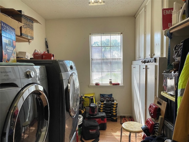 clothes washing area featuring cabinet space, wood finished floors, a textured ceiling, and independent washer and dryer