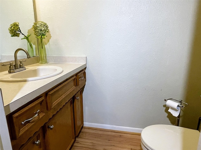 bathroom with baseboards, vanity, toilet, and wood finished floors