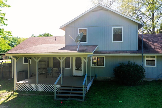 rear view of property featuring a shingled roof, a yard, and central AC unit