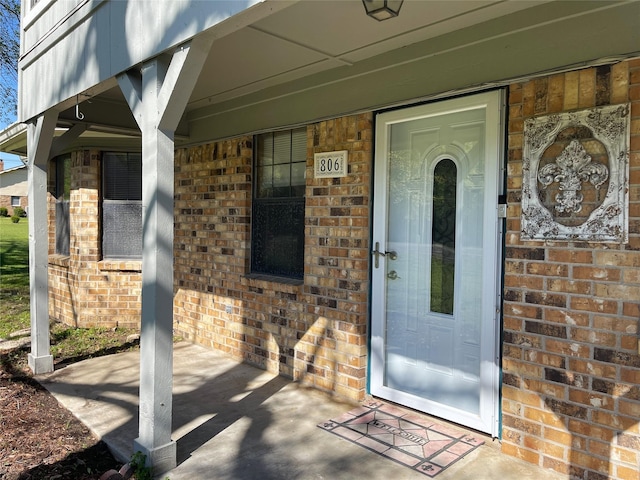 property entrance with brick siding and a porch