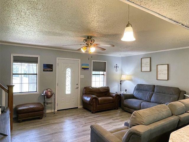 living room with stairs, ornamental molding, plenty of natural light, and wood finished floors