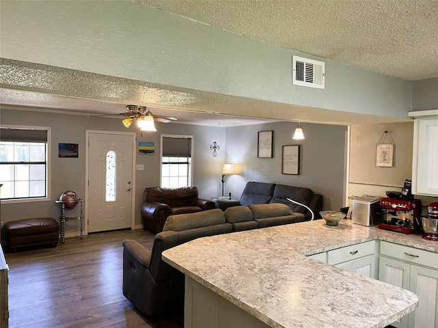 kitchen featuring open floor plan, a peninsula, light countertops, and visible vents