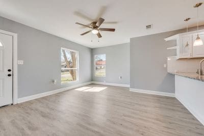 unfurnished living room with a ceiling fan, visible vents, light wood-style flooring, and baseboards