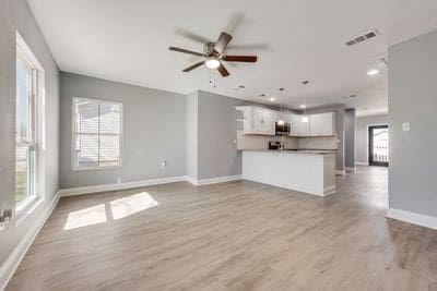 unfurnished living room with a healthy amount of sunlight, baseboards, visible vents, and wood finished floors