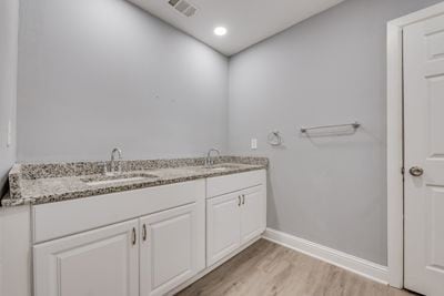 bathroom featuring visible vents, a sink, baseboards, and wood finished floors