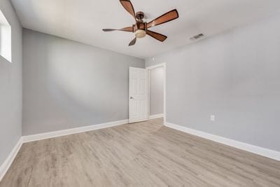 empty room with wood finished floors, visible vents, and baseboards