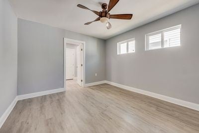 spare room featuring ceiling fan, baseboards, and wood finished floors