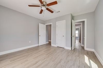 unfurnished bedroom featuring a closet, visible vents, baseboards, and wood finished floors