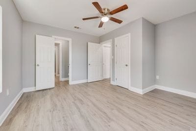 unfurnished bedroom with a ceiling fan, baseboards, and wood finished floors