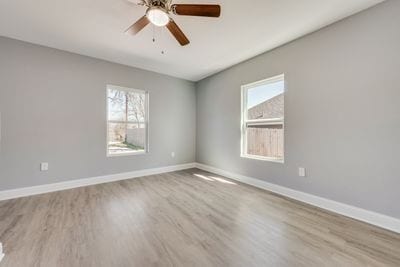 empty room with ceiling fan, baseboards, and wood finished floors