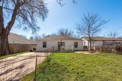 rear view of property with a lawn and fence