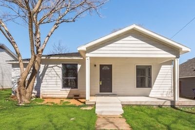 ranch-style home featuring covered porch and a front yard