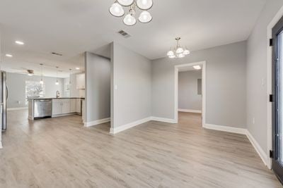 interior space with visible vents, light wood-style flooring, baseboards, and an inviting chandelier