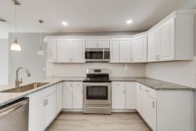 kitchen featuring light wood-style flooring, a peninsula, a sink, white cabinets, and appliances with stainless steel finishes