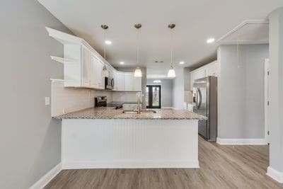 kitchen with light wood-style flooring, appliances with stainless steel finishes, a peninsula, open shelves, and a sink