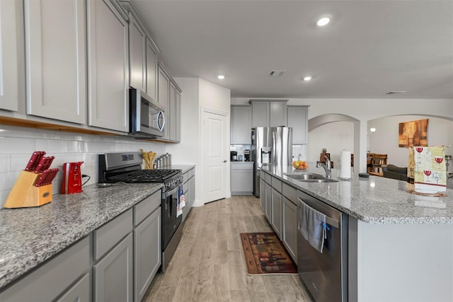 3512 Tunnel Ave, Aubrey, TX 76227 - kitchen with stainless steel appliances, gray cabinetry, arched walkways, a sink, and light stone counters