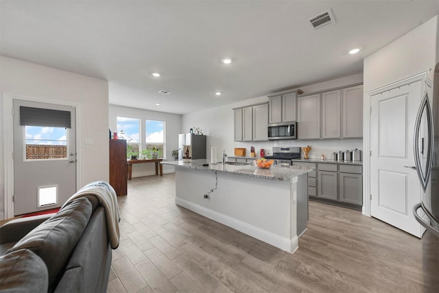 3512 Tunnel Ave, Aubrey, TX 76227 - kitchen featuring appliances with stainless steel finishes, gray cabinets, open floor plan, a sink, and light stone countertops