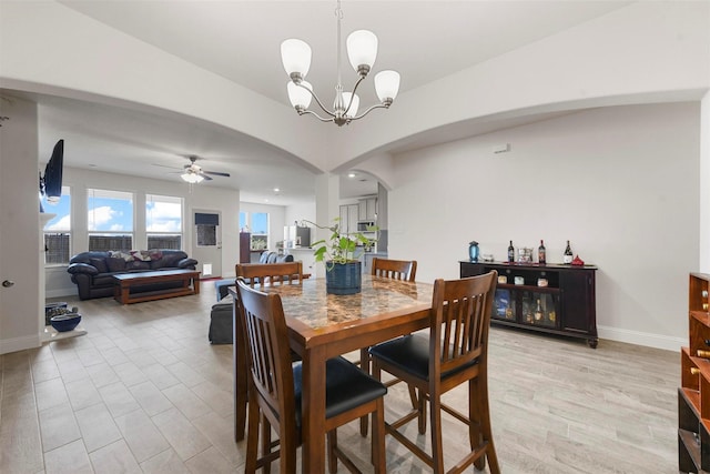 3512 Tunnel Ave, Aubrey, TX 76227 - dining room with arched walkways, a chandelier, a ceiling fan, baseboards, and light wood-type flooring
